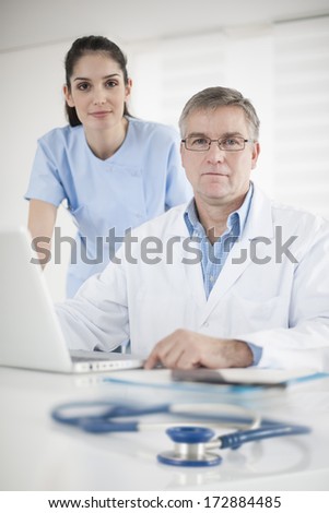 senior doctor and a nurse discussing around a computer