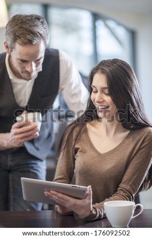 two young people watching a digital tablet in a cafe