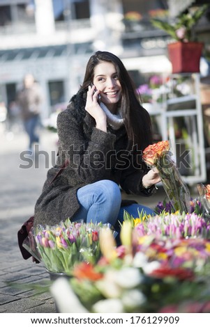 beautiful woman at phone choosing flowers at the florist shop