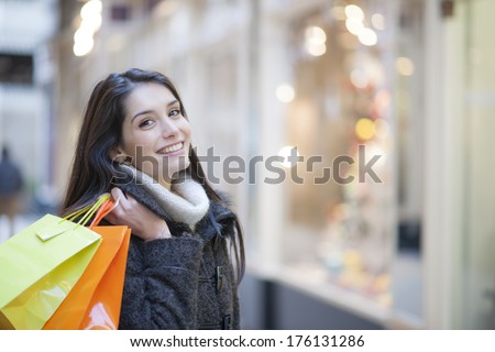 Young Woman With Shopping Bags, Shops Lights In Background