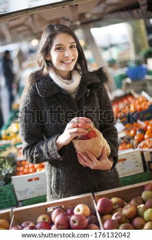 young woman buying apples on a street market