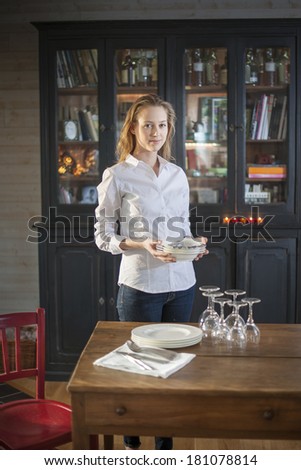 beautiful young woman getting ready to set the table at home to welcoming friends