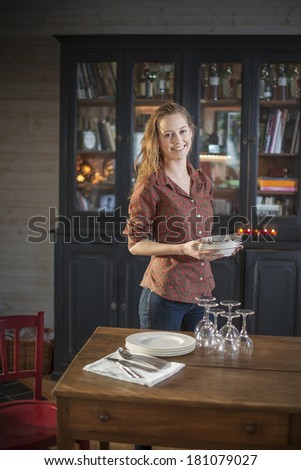 beautiful young woman getting ready to set the table at home to welcoming friends