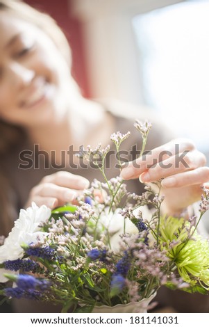 beautiful young woman arranging a bouquet of flowers, focus on the hands  at the foreground