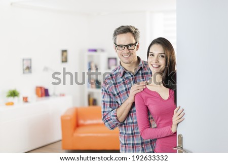couple standing at front door to invite people at home