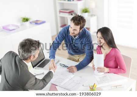 real-estate agent shows a build project  to a young couple