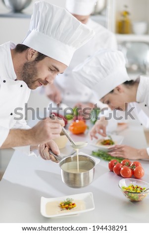 chef preparing a dish his team in the background