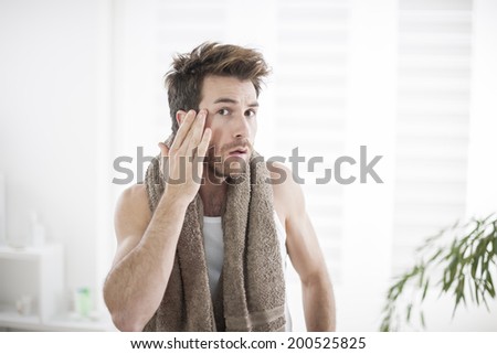 handsome man in his bathroom examines his face