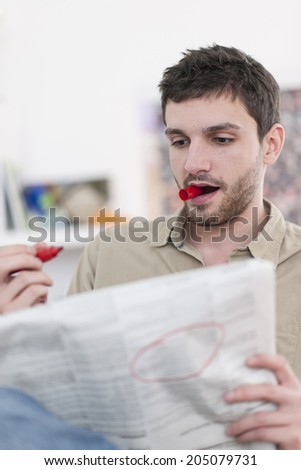 young man looking at the classifieds in the newspaper
