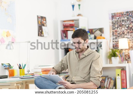 young student sits at his desk and surf on a digital tablet