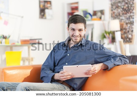 young student lying on a couch surfing  the web  on his digital tablet