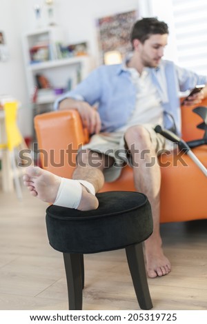 young man with bandaged foot sitting on a sofa