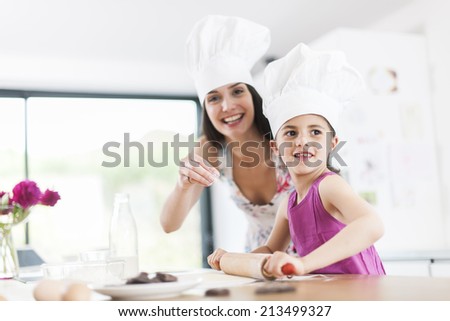 little girl helping her mother prepare a cake