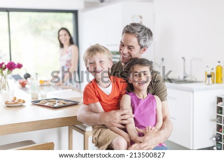 family in the kitchen at breakfast children on their father\'s lap