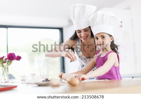 little girl helping her mother prepare a cake