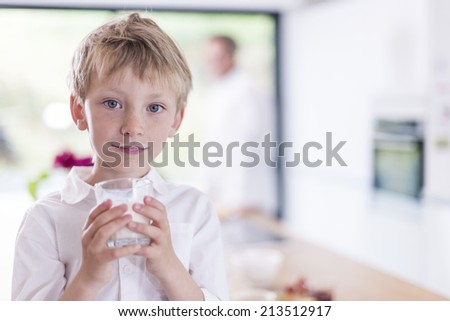 portrait closeup of a boy who drinks a glass of milk in family kitchen