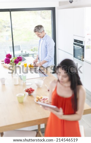 couple in the kitchen at the morning woman using digital tablet at foreground