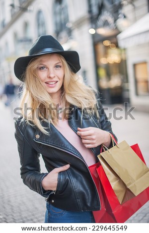 beautiful trendy young woman with hat and leather jacket doing shopping in the city, shopping bags in her arm