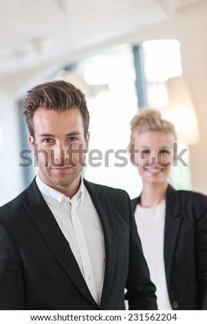 portrait of a business team at office looking at camera, man at foreground and a woman at the background