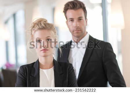 portrait of a business team at office looking at camera, executive woman at foreground and man at the background