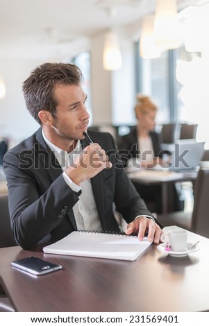 Portrait of a young businessman, sitting and writing at a table
