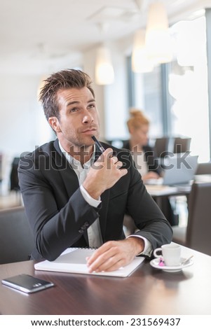 Portrait of a young businessman, sitting and writing at a table