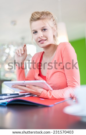 Modern business woman sitting at her contemporary office, using a digital tablet, cup of coffee at foreground