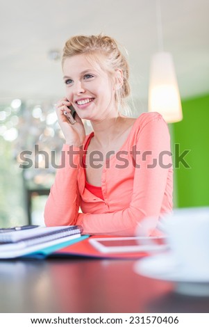 Modern business woman sitting at her contemporary office, calling a partner on her phone