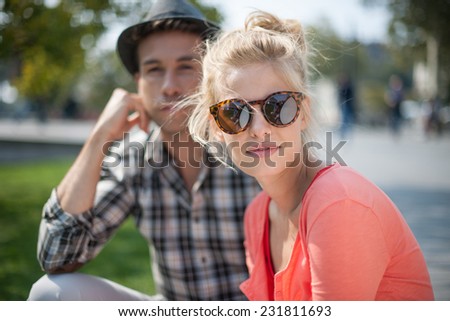 portrait of a modern couple in the city, man wears a hat, woman wears sunglasses
