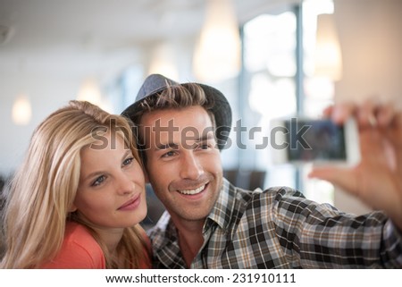 trendy Couple taking a Selfie with a phone, in a coffeeshop