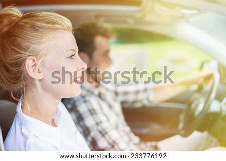 handsome couple sitting in a car, woman's face at foreground and man driving