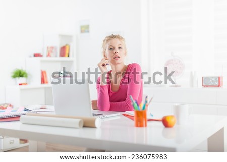 young female self employed, sitting at her office and working on a laptop