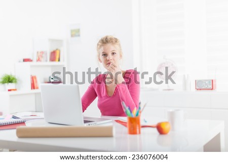 young female self employed, sitting at her office and working on a laptop