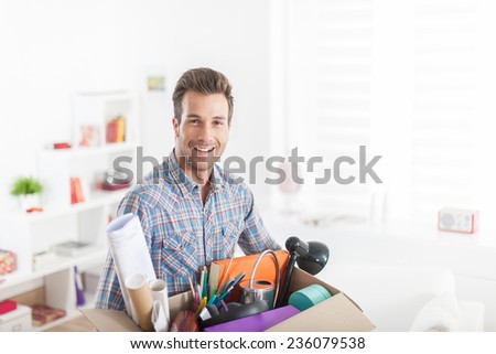 portrait of an handsome man moving in  a new apartment and carrying a box with various objects