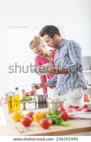 Handsome couple looking for a recipe on a digital tablet for cooking at home, vegetables on the work plan