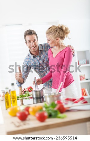 Handsome couple cooking on a cook-top at home, vegetables on the work plan