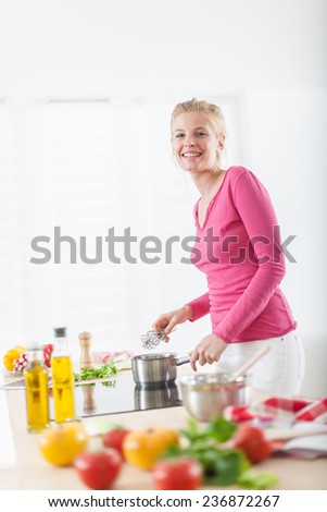 beautiful young woman cooking on a cooktop at home, vegetables on the work plan