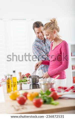 Handsome couple cooking on a cooktop at home, vegetables on the work plan