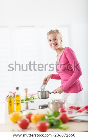 beautiful young woman cooking on a cooktop at home, vegetables on the work plan