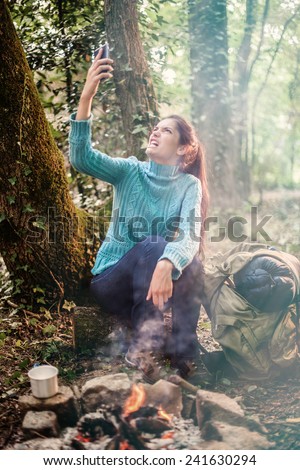 In the forest near a campfire a young angry woman  because a poor reception for her phone
