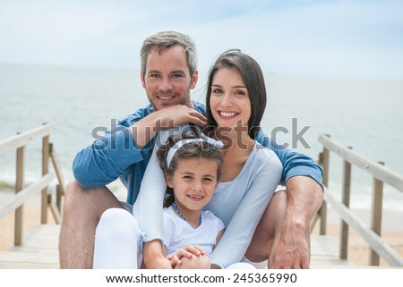 happy family sitting on a wooden pontoon in front of the sea