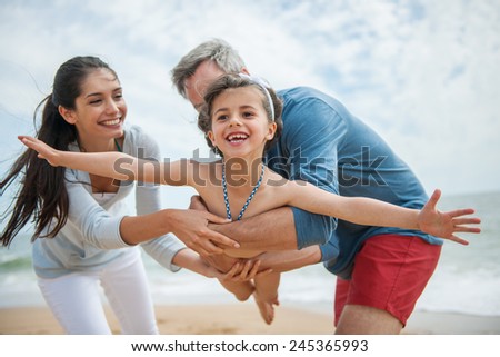A young couple is holding their little girl like a plane