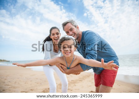 A young couple is holding their little girl like a plane