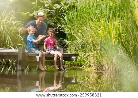 a father with his son and daughter engaged in fishing in a river, they are sitting on a wood pontoon
