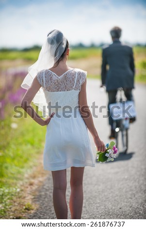 groom leaves his young wife on the side of the road and goes on his bike