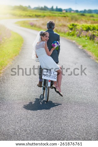 A newlywed couple is taking the road on a bike. They are having fun for their honeymoon