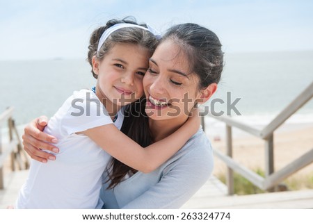 beautiful mom and her daughter at seaside smiling at camera