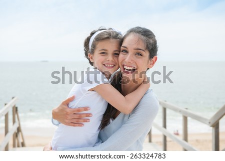 beautiful mom and her daughter at seaside smiling at camera
