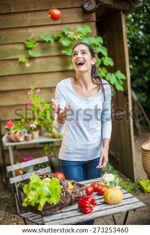 Smiling woman standing in front the garden table with a basket of fresh vegetables