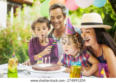 Birthday party in family. Girl blowing candles for her three years old